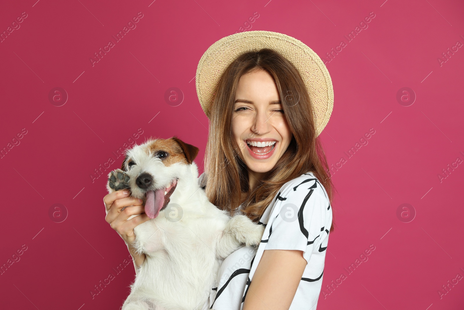 Photo of Young woman with her cute Jack Russell Terrier on pink background. Lovely pet