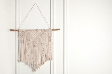 Photo of Stylish beige macrame hanging on white wall. Space for text