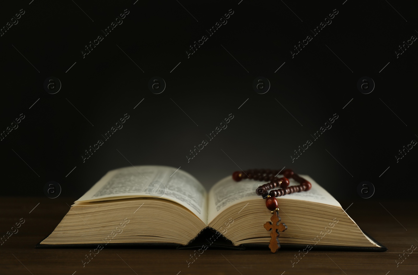 Photo of Open Bible and rosary beads on wooden table, space for text. Lent season