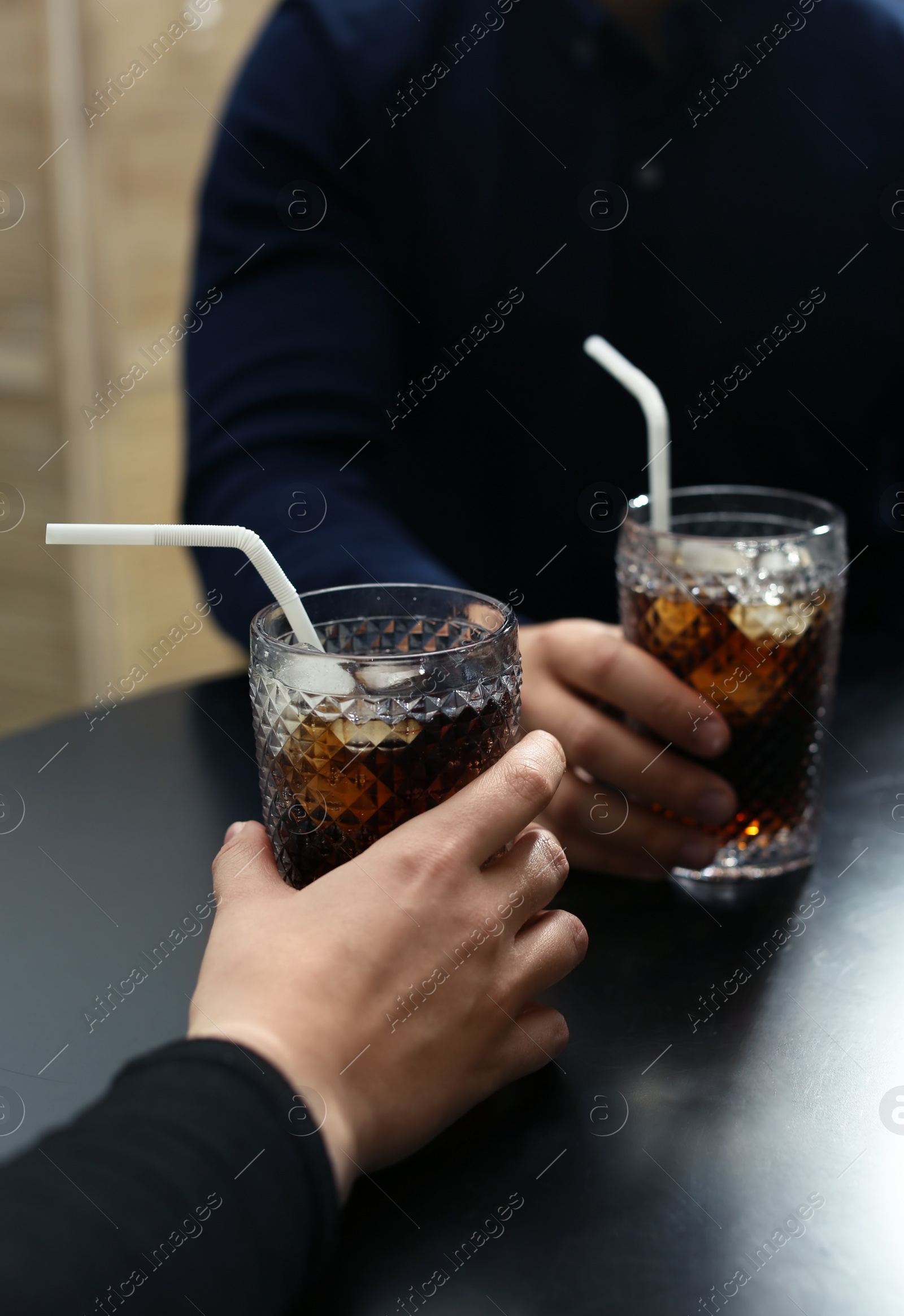 Photo of Couple with glasses of cold cola at table in cafe, closeup