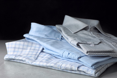 Photo of Stack of classic shirts on light stone table