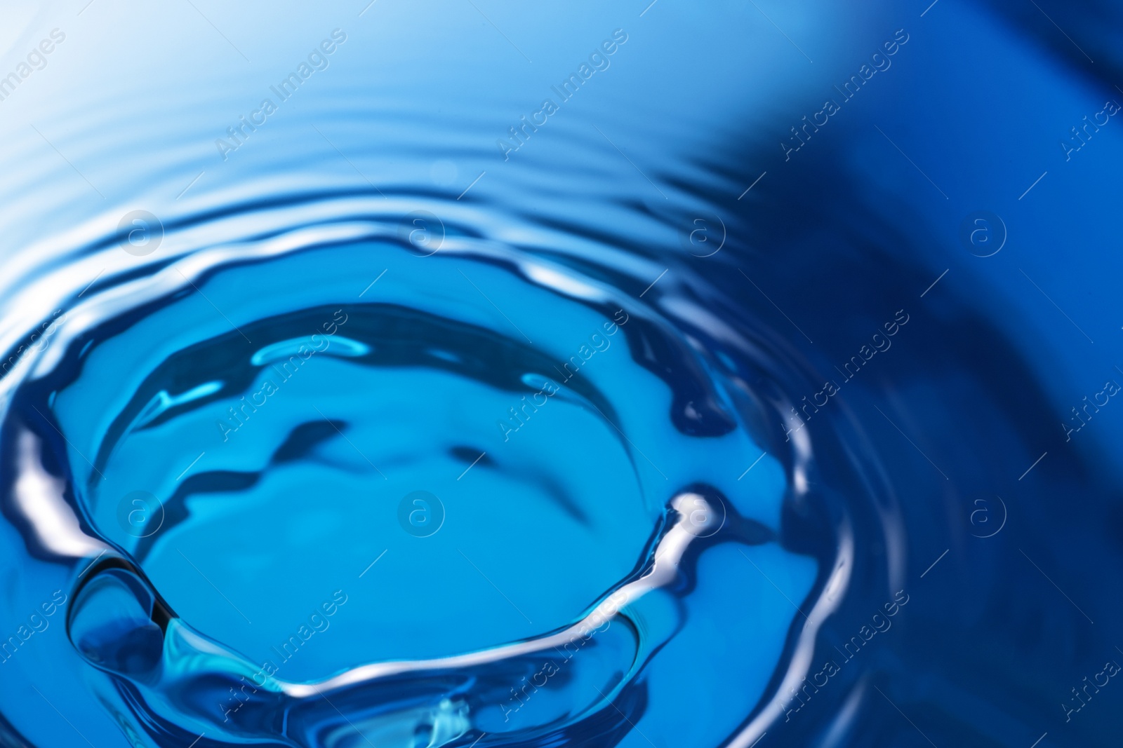 Photo of Splash of clear water on blue background, closeup