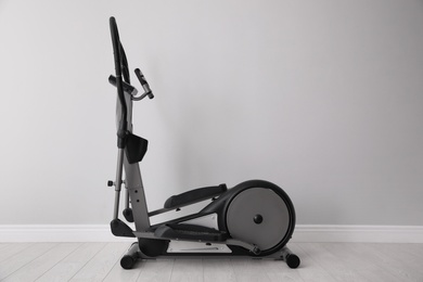 Elliptical machine cross trainer near light grey wall indoors