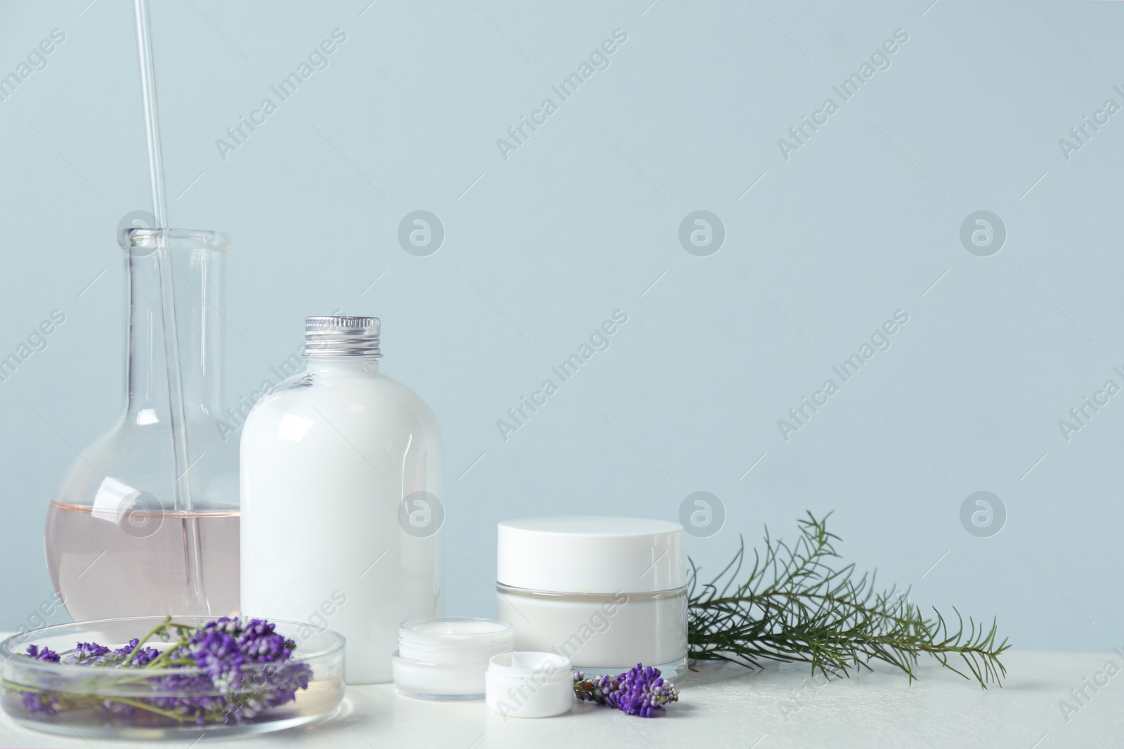 Photo of Herbal cosmetic products, laboratory glassware and ingredients on white table, space for text