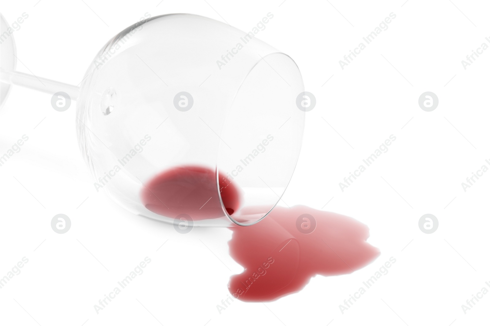 Photo of Transparent glass and spilled exquisite red wine on white background