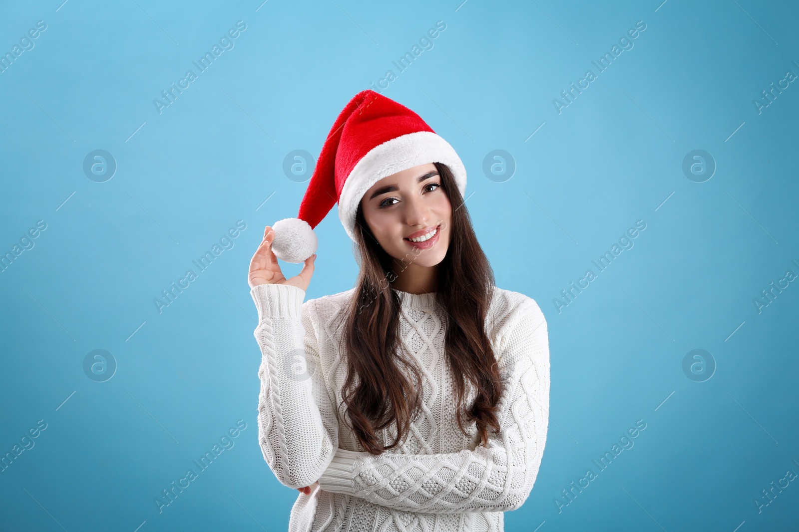 Photo of Beautiful woman wearing Santa Claus hat on light blue background