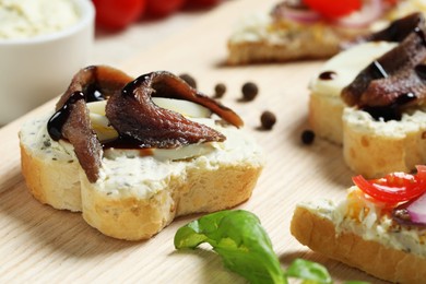 Delicious sandwiches with anchovies on wooden table, closeup