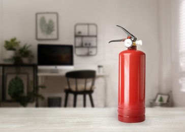 Image of Fire extinguisher on white wooden table in office. Space for text