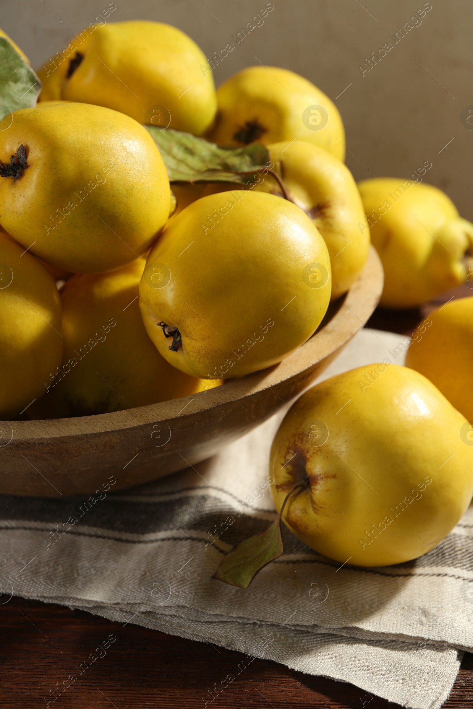 Photo of Tasty ripe quince fruits in bowl on wooden table