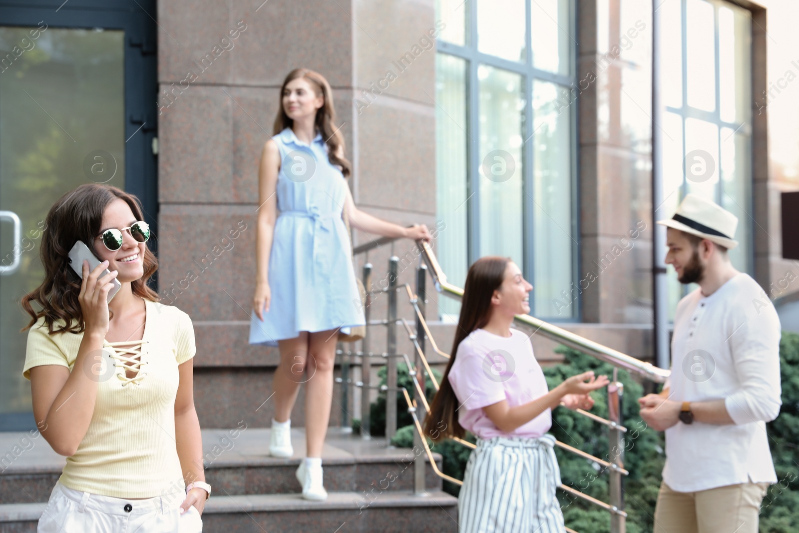 Photo of Young woman talking on phone near modern building