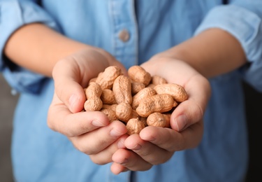 Photo of Woman holding raw peanuts in hands, closeup