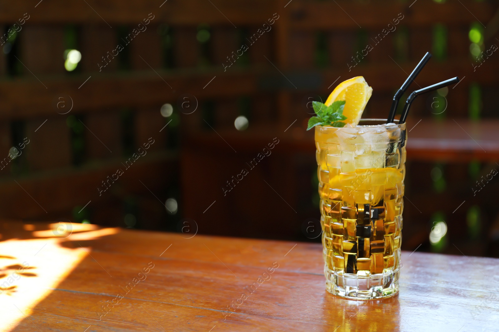 Photo of Glass of delicious cocktail with ice on table in bar