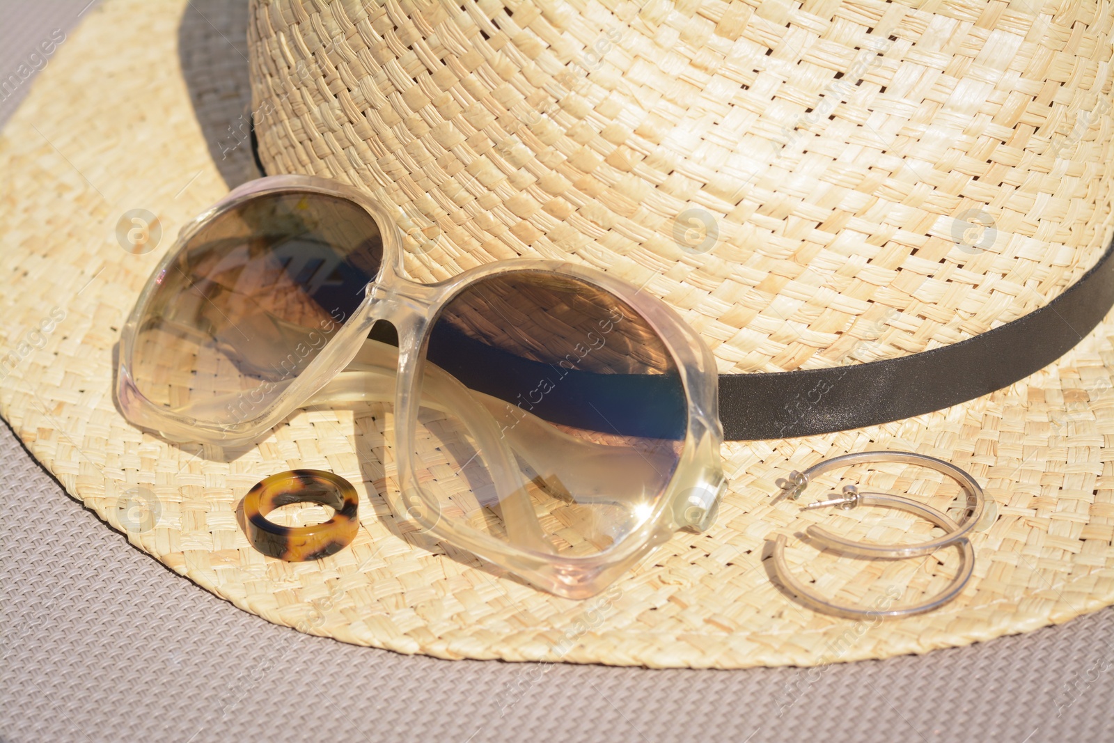 Photo of Stylish hat, sunglasses and jewelry on grey surface, closeup