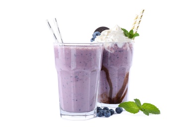 Photo of Tasty milk shakes in glasses with blueberries on white background