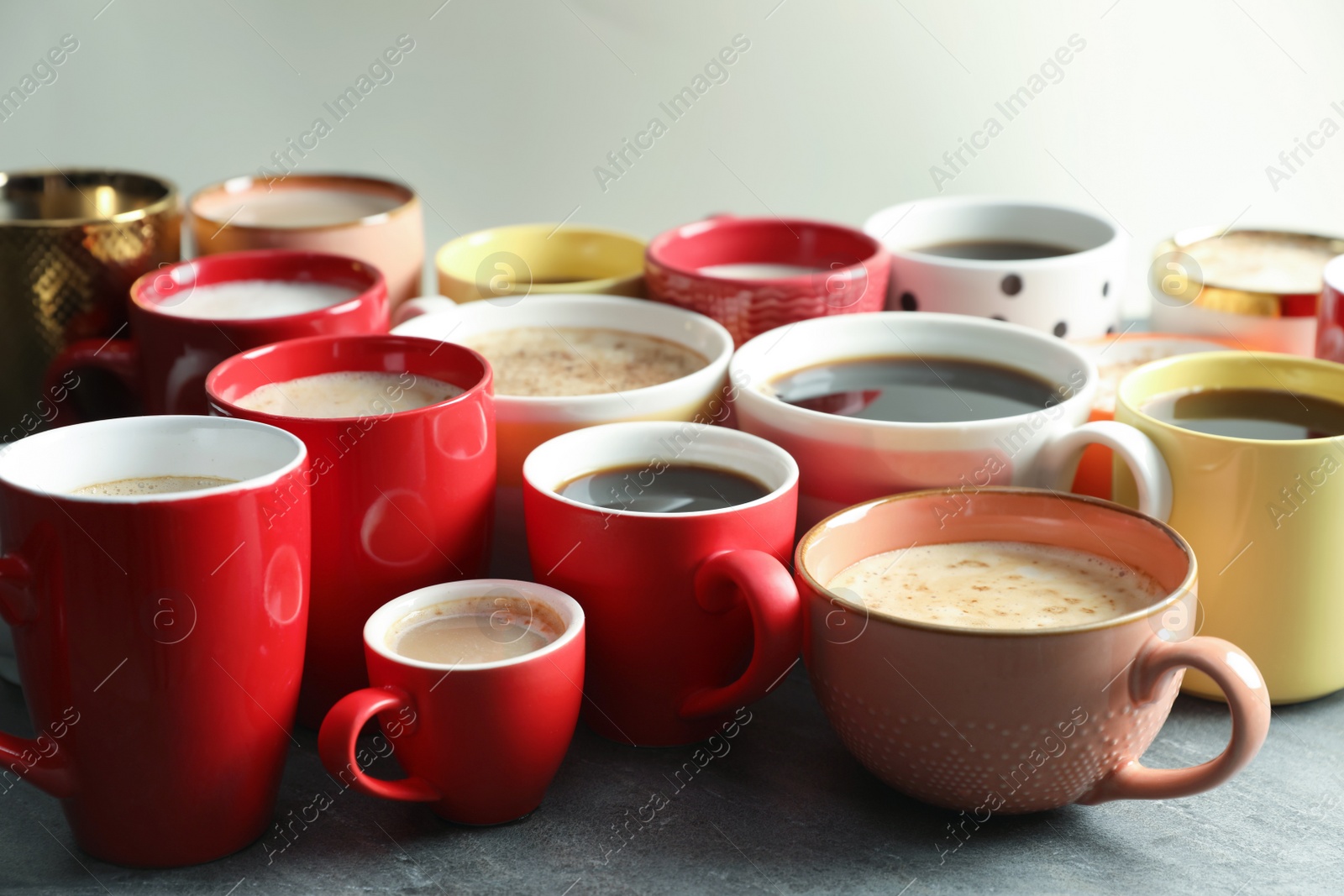 Photo of Many cups of different coffees on grey table