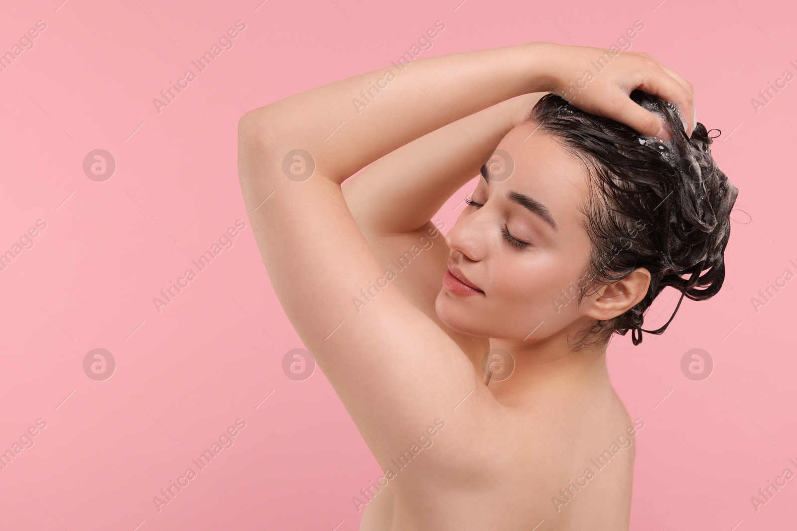 Photo of Beautiful woman washing hair on pink background. Space for text