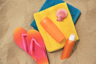 Photo of Flat lay composition with sunscreens on sand. Sun protection care