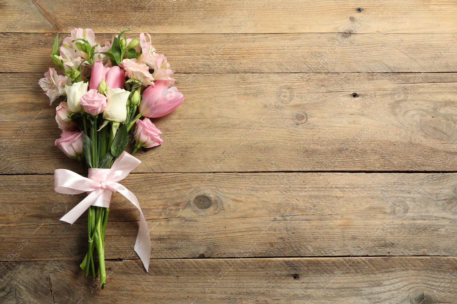 Photo of Happy Mother's Day. Bouquet of beautiful flowers tied with pink ribbon on wooden table, top view. Space for text