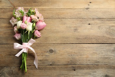 Happy Mother's Day. Bouquet of beautiful flowers tied with pink ribbon on wooden table, top view. Space for text