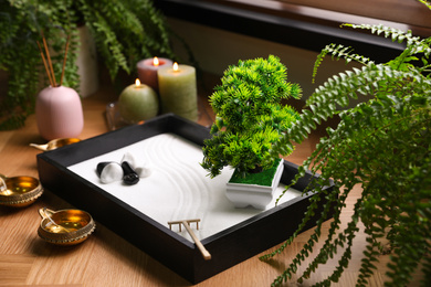 Photo of Beautiful miniature zen garden, candles and oil lamps near window indoors