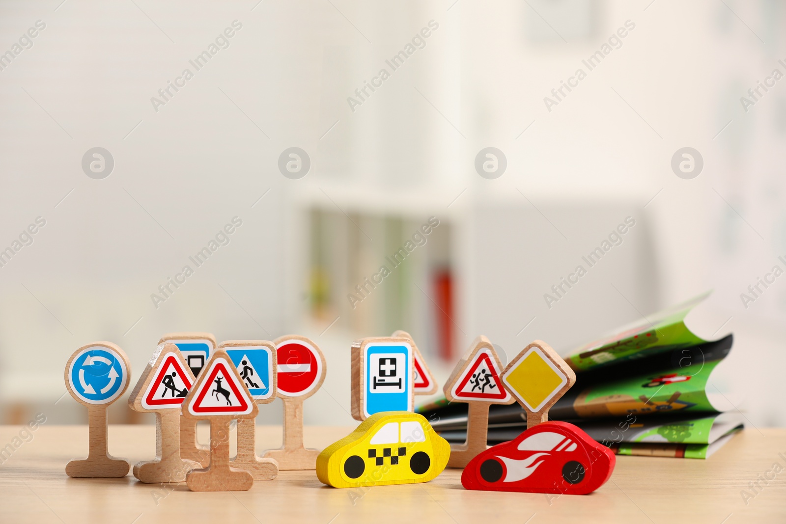 Photo of Set of wooden road signs and cars on table indoors. Children's toys