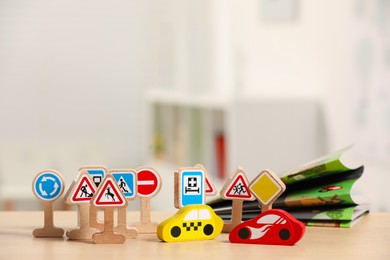 Set of wooden road signs and cars on table indoors. Children's toys
