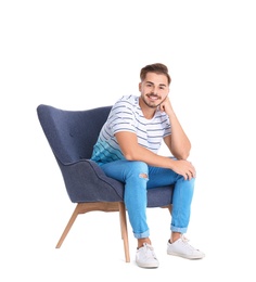 Handsome young man sitting in armchair on white background