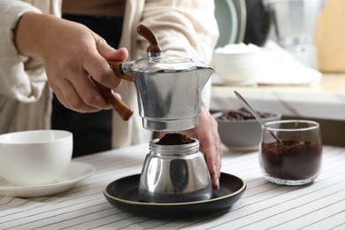 Photo of Brewing aromatic coffee. Woman with moka pot at table in kitchen, closeup