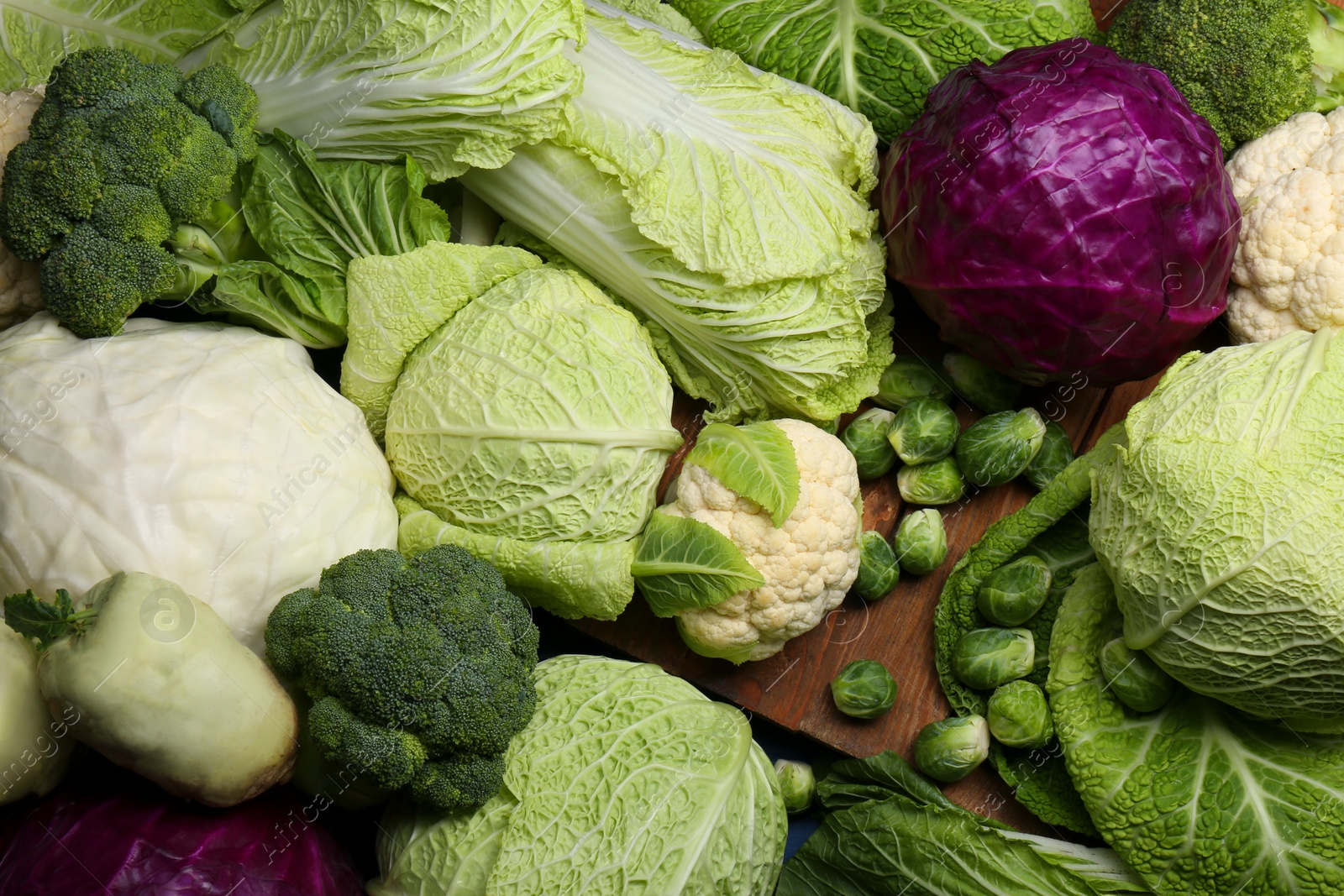 Photo of Many different types of cabbage on wooden table, flat lay