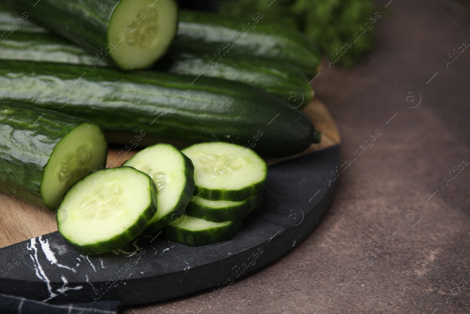 Photo of Fresh whole and cut cucumbers on brown textured table, closeup