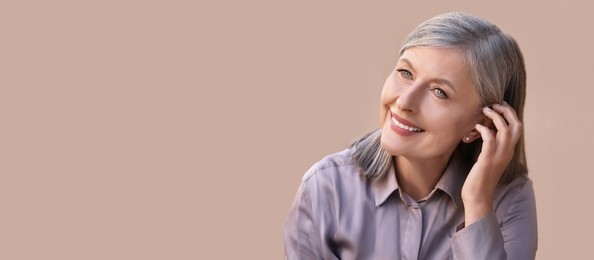 Image of Portrait of beautiful mature woman on beige background. Banner design with space for text