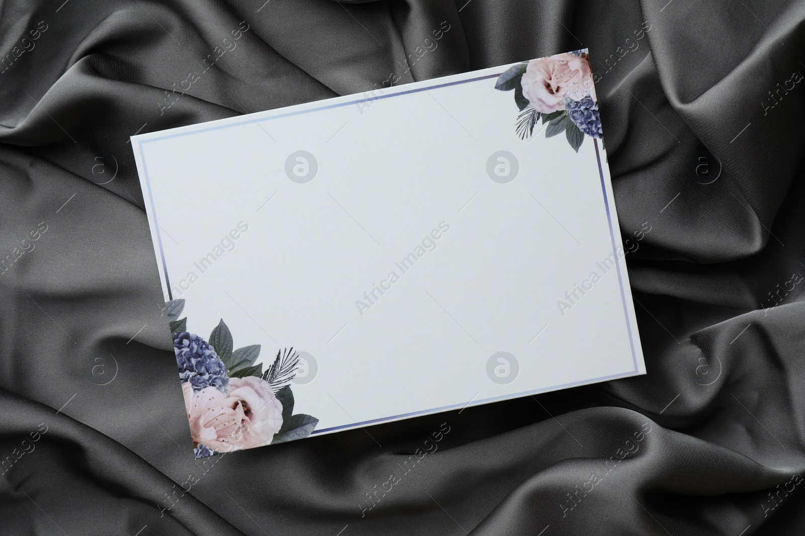 Photo of Blank invitation card on black fabric, top view