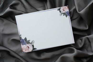 Photo of Blank invitation card on black fabric, top view