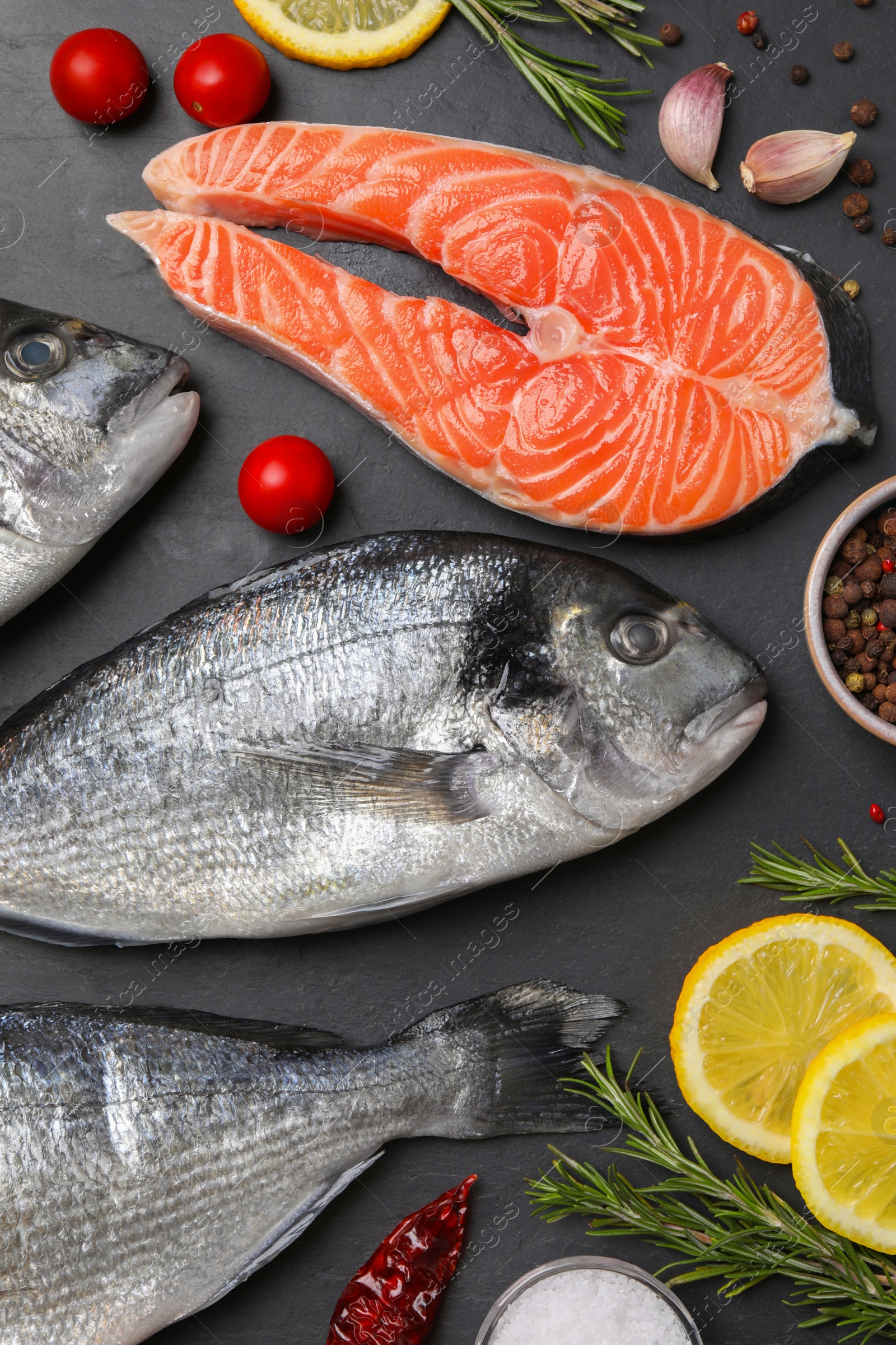 Photo of Fresh raw dorado fish, salmon and lemon slices on grey table, flat lay