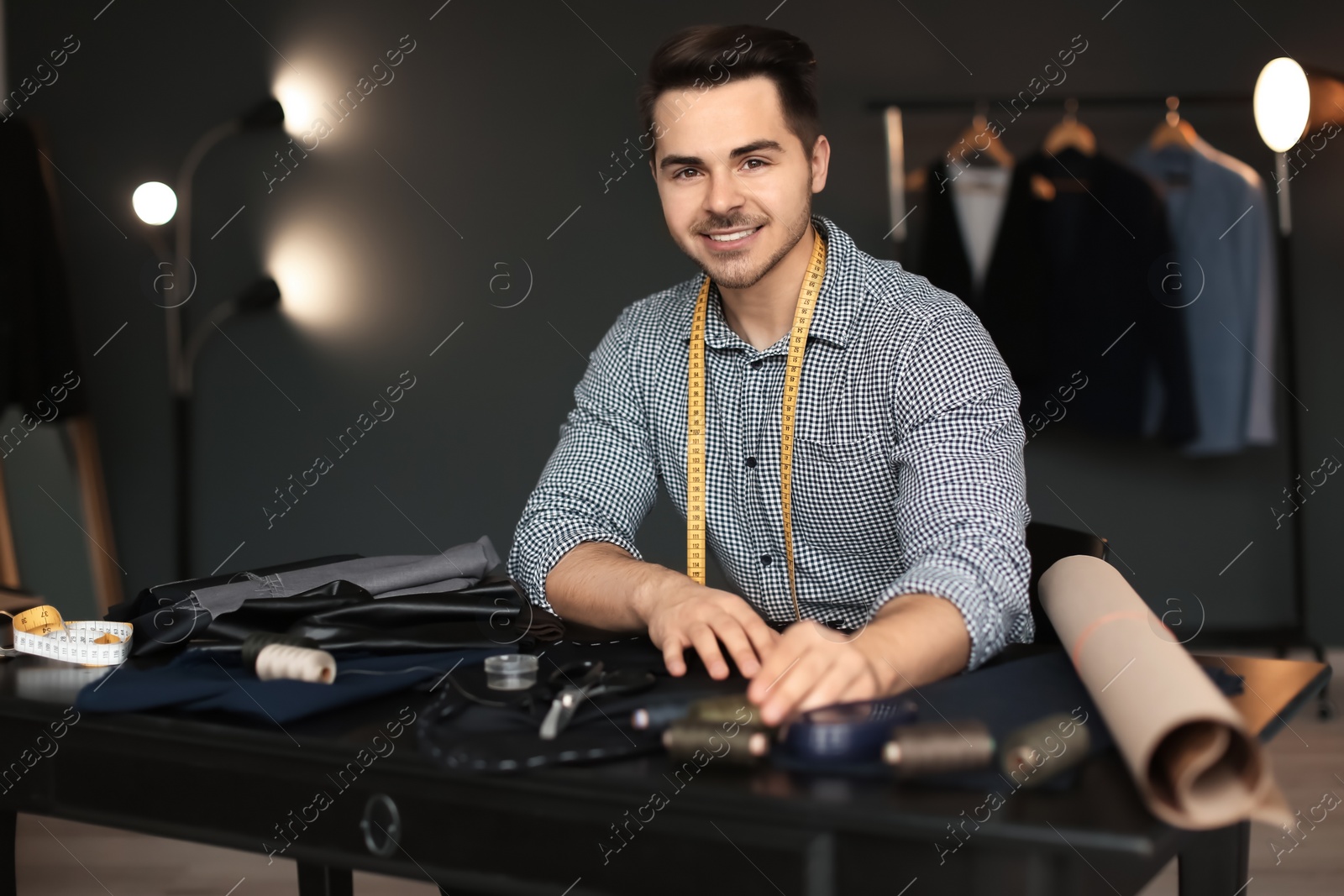 Photo of Young tailor working with sewing pattern in atelier