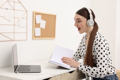 E-learning. Young woman using laptop during online lesson at table indoors