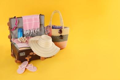 Photo of Bag and packed vintage suitcase with different beach objects on orange background, space for text. Summer vacation