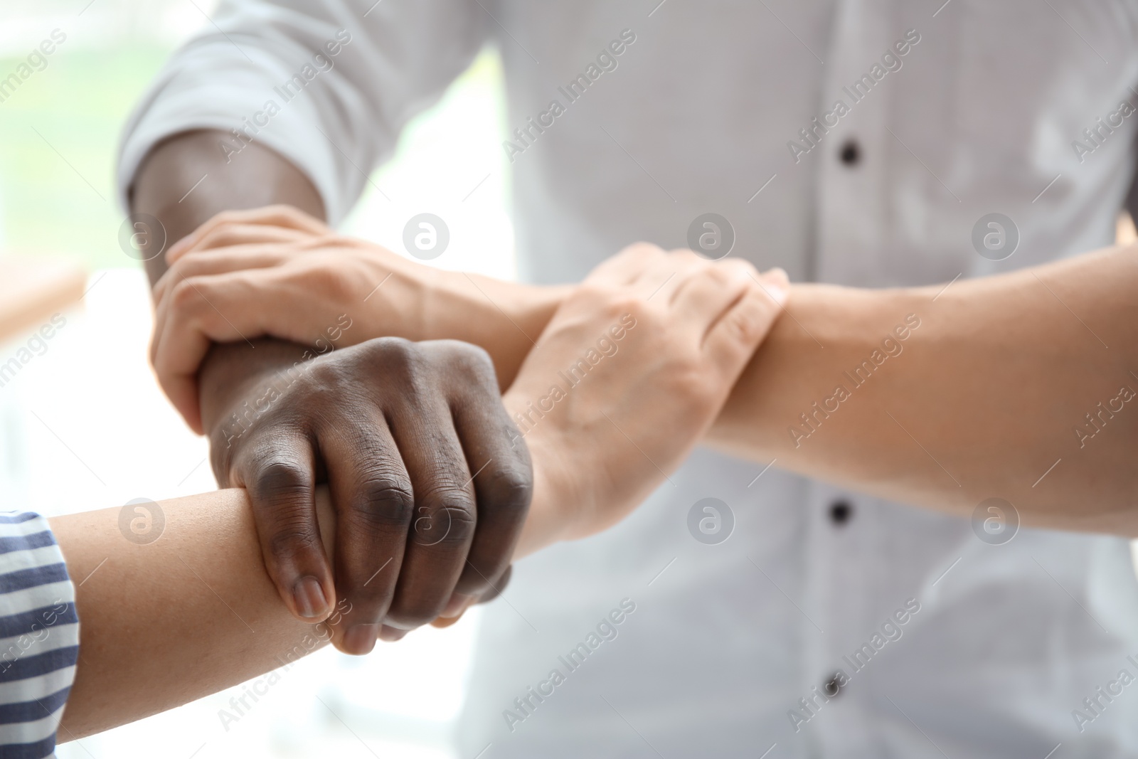 Photo of People holding hands on light background, closeup. Unity concept