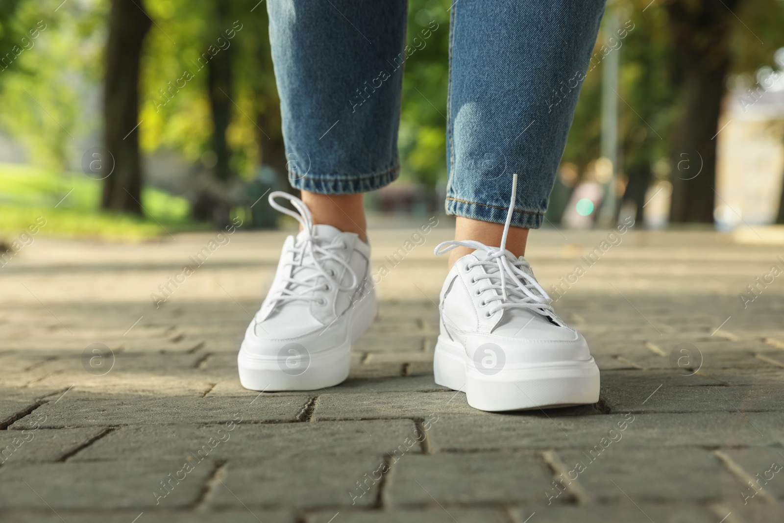 Photo of Woman in stylish sneakers walking on city street, closeup