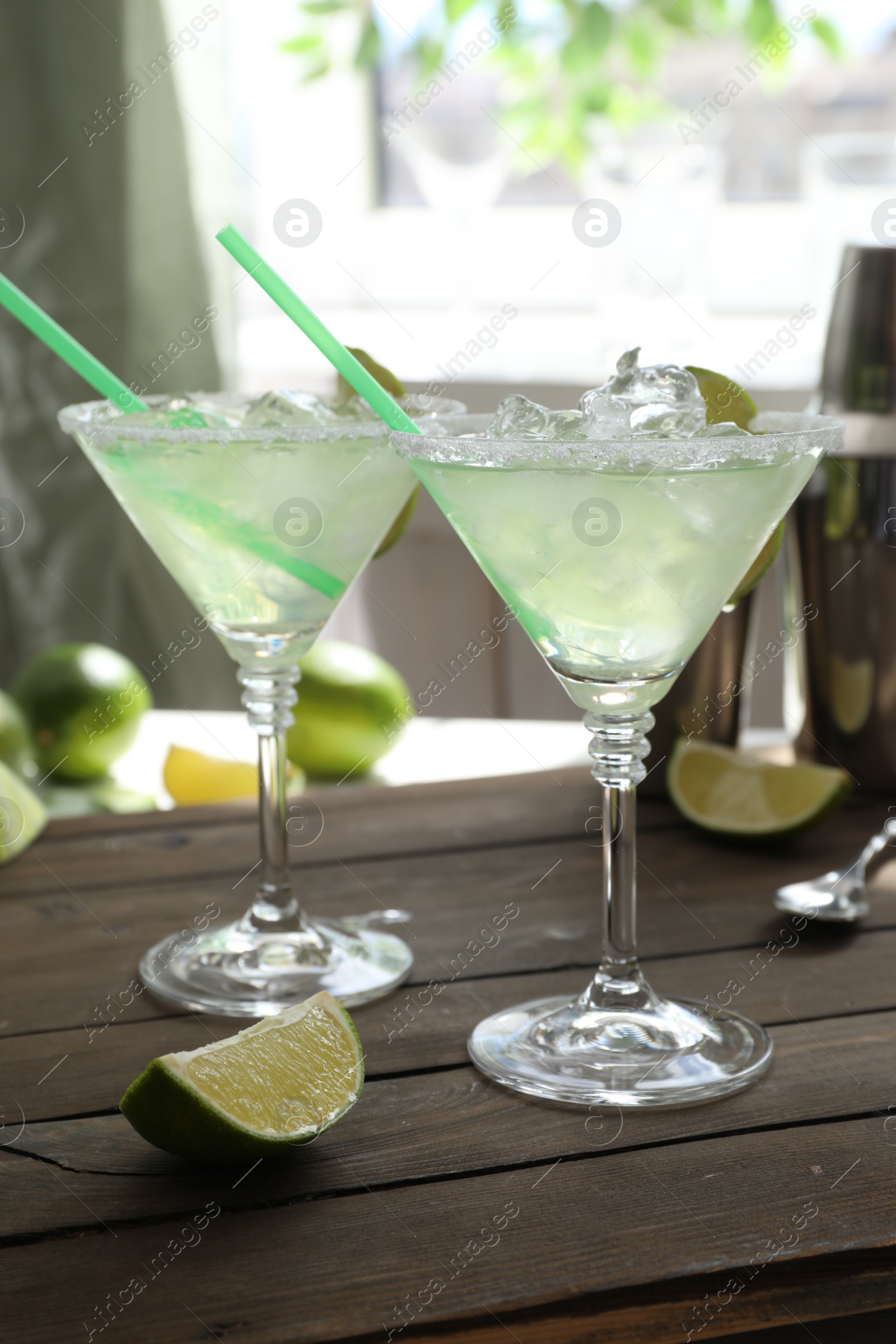 Photo of Delicious Margarita cocktail in glasses and lime on wooden table