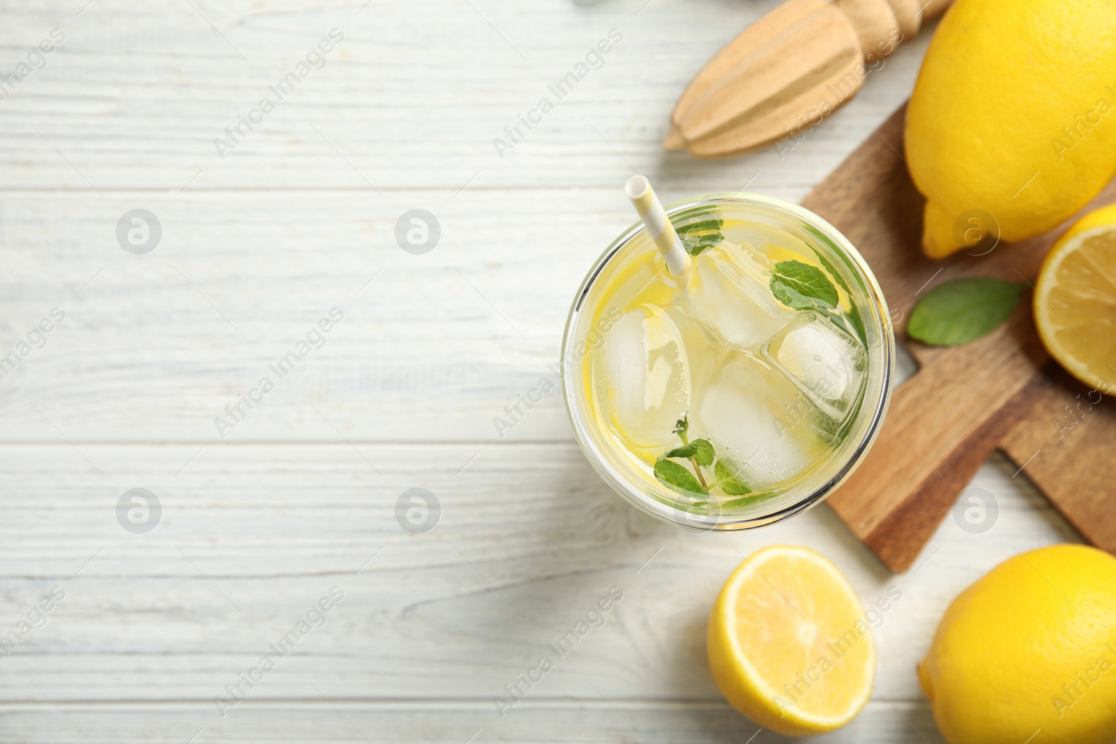 Photo of Cool freshly made lemonade, reamer and fruits on white wooden table, flat lay. Space for text