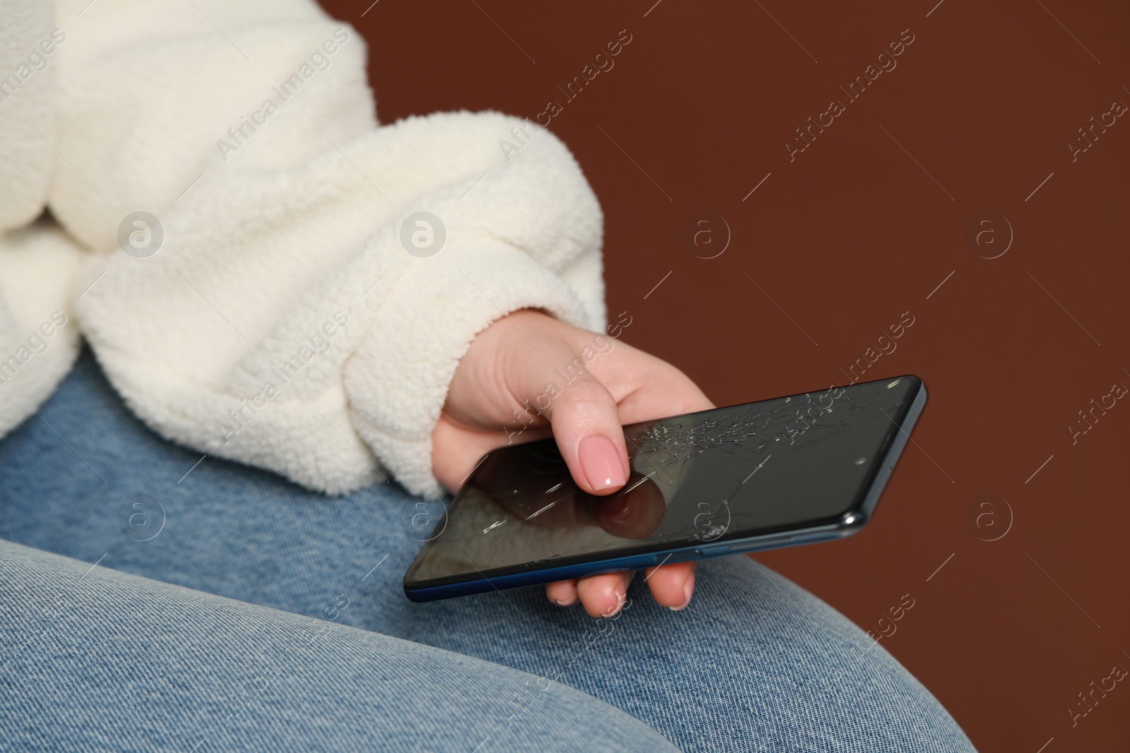 Photo of Woman with damaged smartphone on brown background, closeup. Device repairing