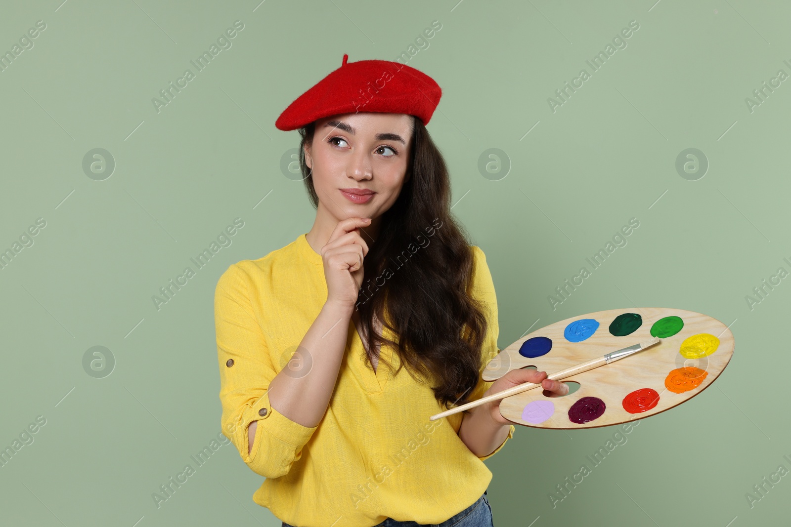 Photo of Woman with painting tools on pale green background. Young artist