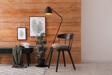 Photo of Stylish room interior with floor lamp, beautiful paintings and potted eucalyptus plant