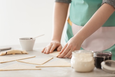 Photo of Woman preparing tasty croissants with chocolate paste on table, closeup