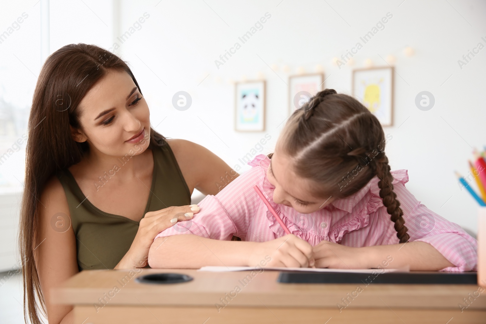 Photo of Young woman and little girl with autistic disorder drawing at home