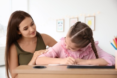 Young woman and little girl with autistic disorder drawing at home