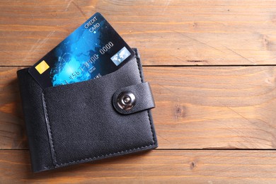 Photo of Credit card and leather wallet on wooden table, top view. Space for text