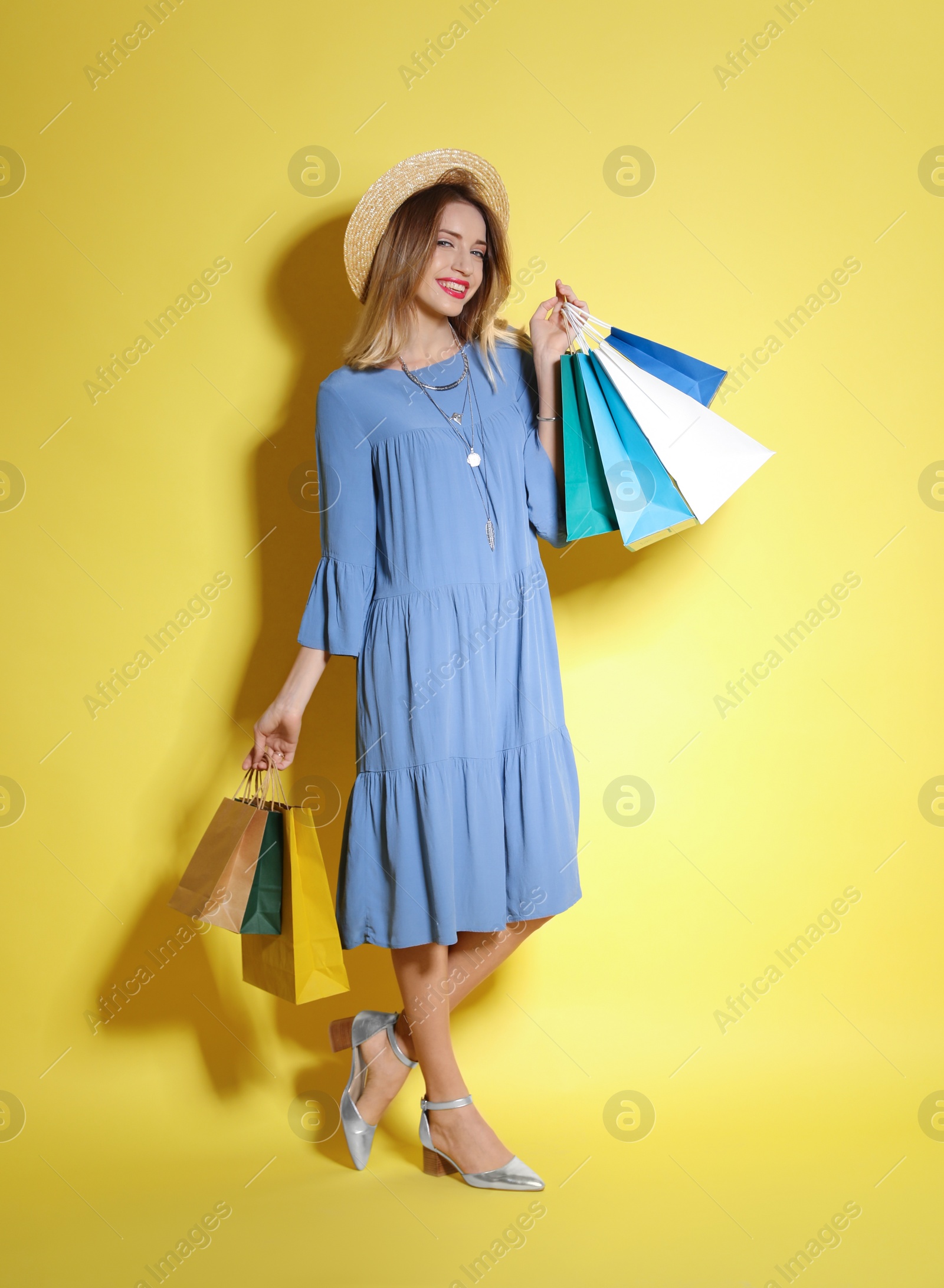 Photo of Beautiful young woman with shopping bags on color background