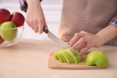 Woman cutting ripe apple at table